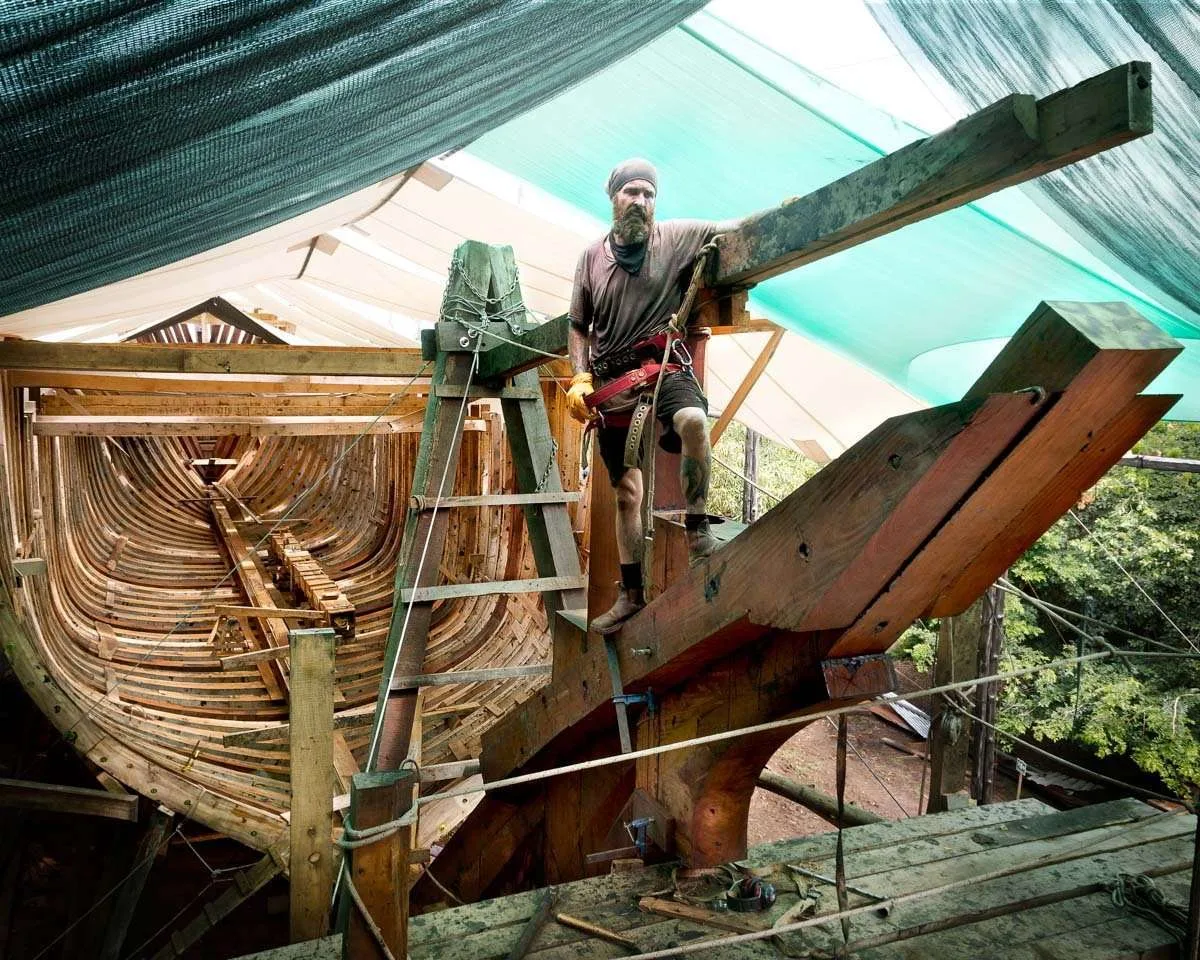 A WOODEN CARGO SHIP, STEAMING HOT UNDER A TROPICAL SUN